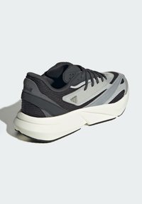 Čierna a sivá športová obuv z kombinácie sieťoviny a syntetických materiálov, ktorá má hrubú bielu podrážku a textúrované akcenty na hornej časti.