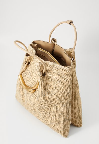Beige woven handbag with a gold-tone handle, partially open to reveal a tan interior. Stylish and modern design, suitable for various occasions.