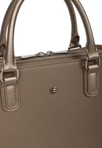 Beżowa skórzana torba na ramię z teksturowaną powierzchnią, podwójnymi uchwytami i zamkiem na górze. Posiada metalowy detal z zatrzaskiem z przodu.