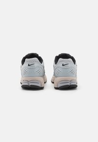 Nike-sneakers med en mesh-överdela i ljusgrått och svart, med en texturerad häl, dämpad sula och subtil logotyp på baksidan.