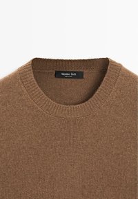 Hnědý pletený svetr s kulatým výstřihem. Má hladkou texturu, těsné žebrování na límci a černou značku s nápisem "Massimo Dutti."