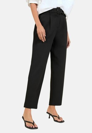 Pantaloni neri su misura con vita cinture, gamba dritta e pieghe frontali. Indossati con sandali neri con tacco e cinturini.