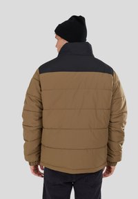 Padded jacket with a brown lower section and black upper section. Features a high collar and elastic cuffs for a snug fit.