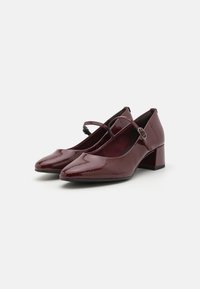 Talons en cuir verni bordeaux avec un nez pointu, une bride au niveau de la cheville et un talon bloc modeste. Texture lisse et finition brillante.