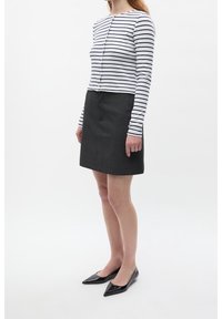 Blusa de rayas de manga larga en blanco y azul marino; combinada con una falda ajustada gris oscuro; bailarinas negras de punta afilada; tela suave y diseño a medida.