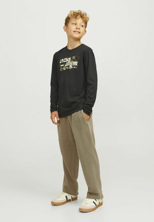 Svart långärmad tröja med grafisk text, kombinerad med beige sweatpants och vita sneakers. Outfiten har en avslappnad passform och en casual stil.