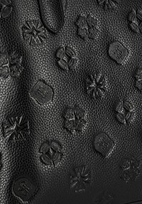 Zwarte leren handtas met geperste patronen en logo's over het oppervlak, met een gestructureerde afwerking en subtiele glans.