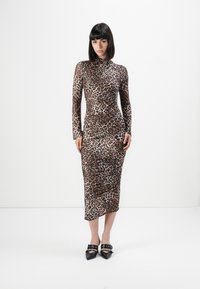 Šaty s dlhým rukávom a leopardím vzorom, priliehavé, s vysokým golierom a dĺžkou do polovice lýtok. Nosené s čiernymi špicatými topánkami s prackovými ozdobami.