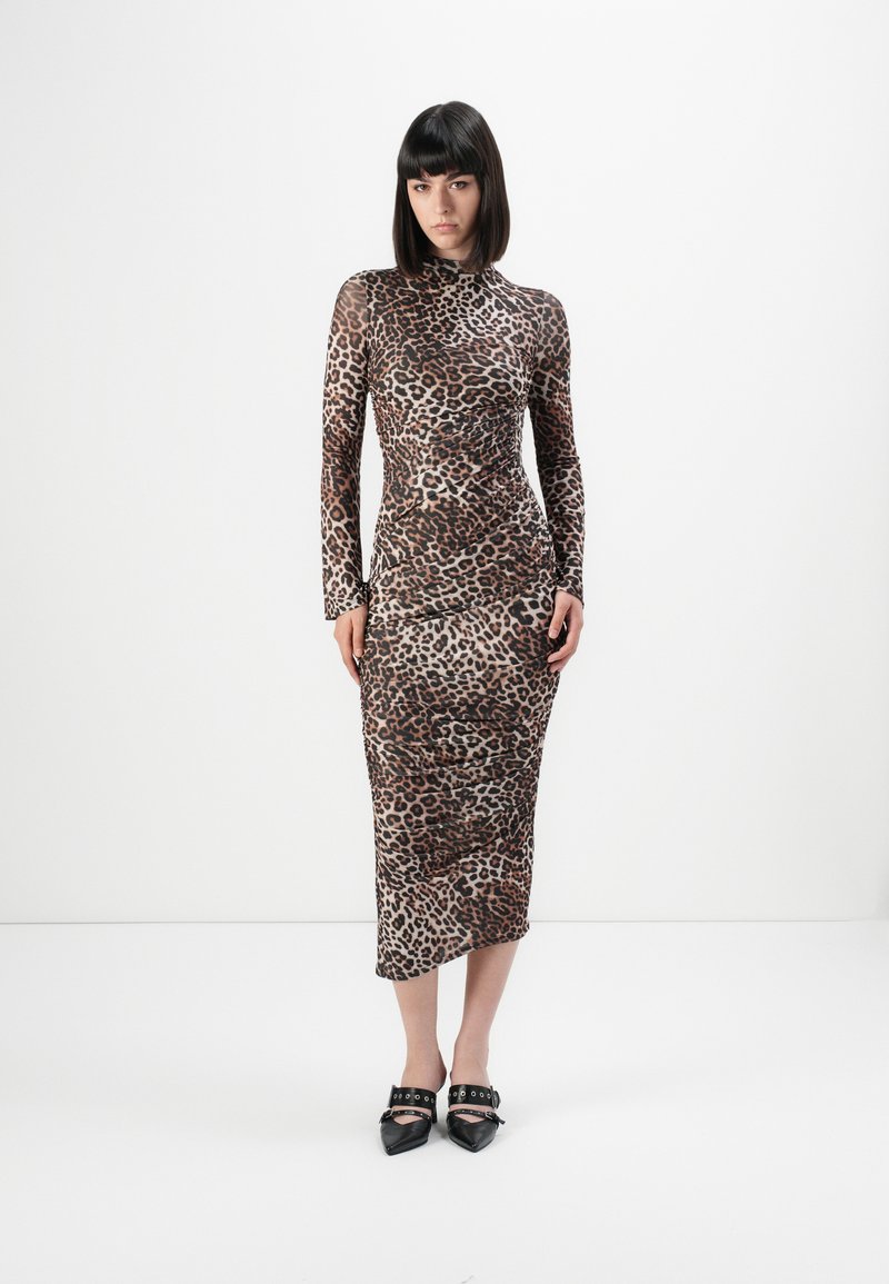 Šaty s dlhým rukávom a leopardím vzorom, priliehavé, s vysokým golierom a dĺžkou do polovice lýtok. Nosené s čiernymi špicatými topánkami s prackovými ozdobami.