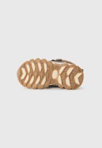 Suola di scarpe da esterno con gomma testurizzata, una combinazione di colori marrone e beige, con un design robusto per aderenza e trazione.