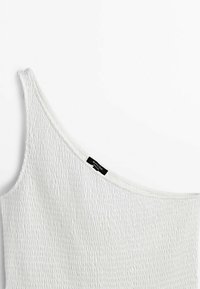 Top bianco off-shoulder realizzato in tessuto texturizzato con un motivo arricciato. Presenta un ampio scollatura e un'etichetta di marca nera sul lato.