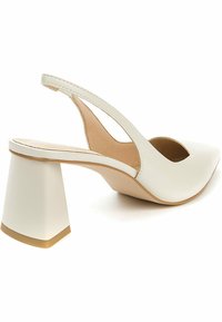 Chaussure à bride arrière en cuir blanc avec un talon bloc large et incliné et un bout pointu, vue de côté et légèrement arrière.