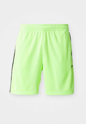 Neon zöld sportnadrág, rugalmas derékkal, fekete oldalsó csíkokkal és könnyű, légáteresztő anyagból készült.