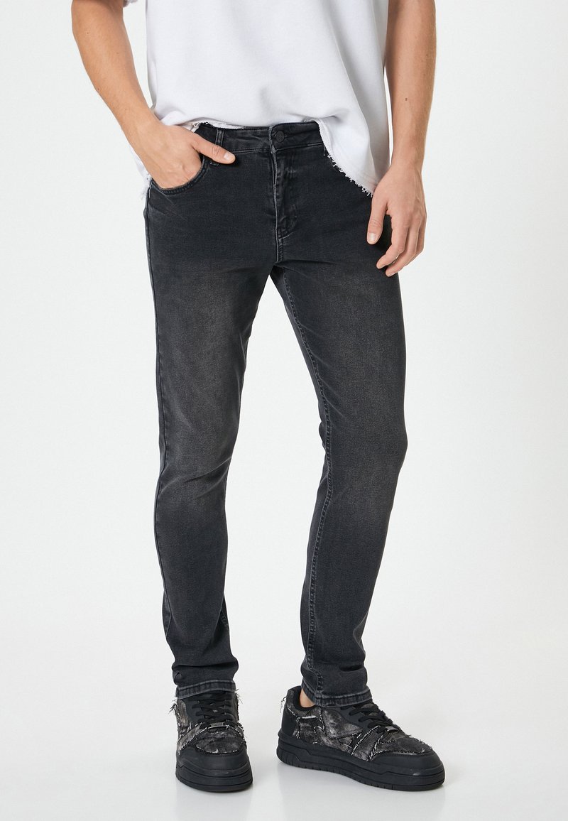 Svarta slim-fit jeans med en urtvättad finish, fem fickor och knappgylf. Bärs med texturerade svarta sneakers. Slät tygkvalitet.
