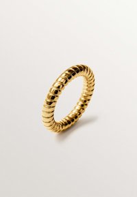 Anillo dorado con un diseño estriado que presenta secciones alternas lisas y texturizadas, creando un contraste visual. Forma delgada y circular.