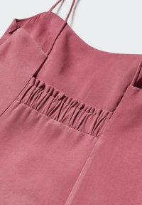 Rosa ärmelloses Oberteil mit einem gerafften Detail auf der Vorderseite, aus glattem Stoff gefertigt, mit dünnen Trägern und einem schlichten, klaren Design.