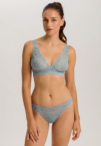 Svetle modrý krajkový bralet a odpovídající tanga, které mají květinové vzory, hluboký výstřih a zoubkované okraje. Měkká, poloprůhledná textura.