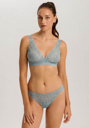 Vaaleansininen pitsinen bralette ja matching-thong, jossa on kukkakuviot, syvä kaula-aukko ja aallotetut reunat. Pehmeä, puoliksi läpikuultava pinta.