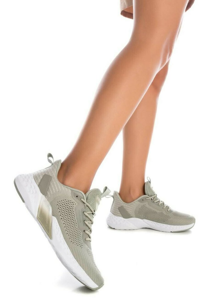 Zapatillas deportivas de color gris claro, fabricadas con una malla transpirable de textura estampada, con una suela blanca y sutiles detalles de acento en los lados.