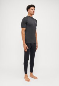 Zwarte wetsuit-top met korte mouwen en lange leggings, gemaakt van glad, rekbaar materiaal. Beschikt over een logo op de borst. Strak ontwerp.