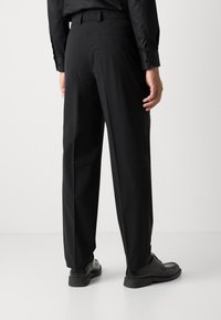Black trousers with a straight leg design, featuring a smooth texture, standard belt loops, and a clean finish. Paired with black shoes.