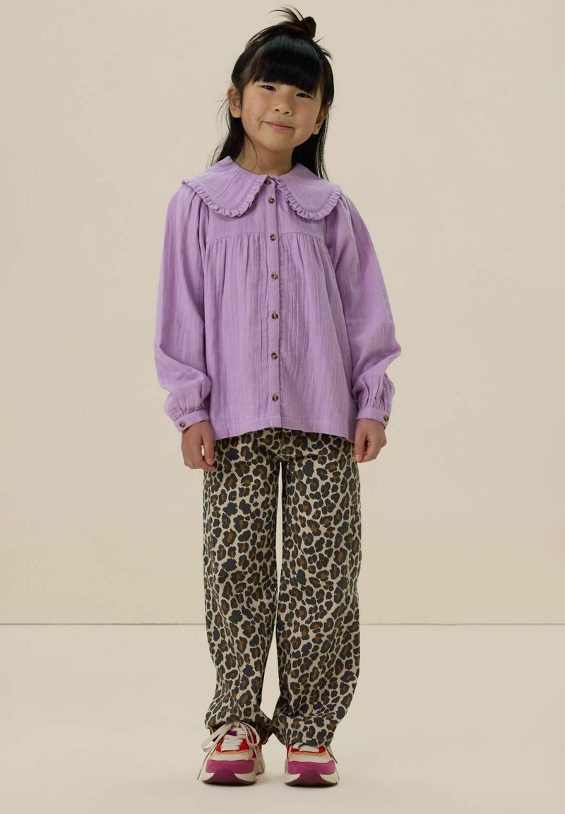 Lavender button-up shirt with large collar and ruffle detail, paired with loose-fitting leopard print pants and white sneakers.