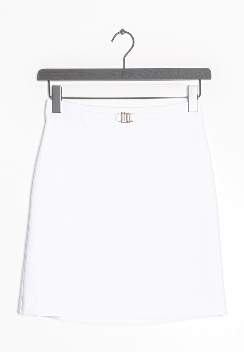 Jupe blanche en ligne A accrochée à un cintre noir avec un petit détail de boucle rectangulaire argentée à la taille sur fond blanc.