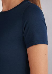 Mörkblå t-shirt med kort ärm och rund halsringning. Slät, lättviktsmaterial med en figurnära design. Sömmarna är prydliga och välavslutade.