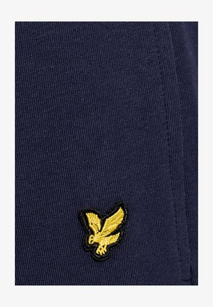 Gelb besticktes Adler-Logo auf dunkelblau geripptem Stoff mit sichtbaren Nahtstichen.