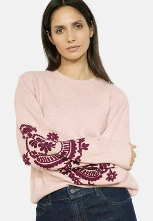 Pull en tricot rose clair à manches longues, avec une broderie florale bordeaux foncé sur les manches. Texture douce, encolure ronde, coupe décontractée.