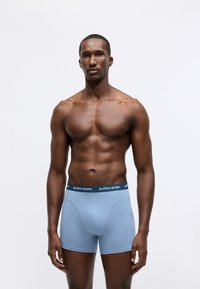 Mėlynos boxer glaudės, pagamintos iš minkštos medžiagos, su kontrastiniu juodu juosmeniu, ant kurio išsiuvinėtas "BJÖRN BORG" logotipas, lygaus tekstūros, prigludusio dizaino.