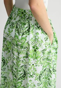 Falda verde con un diseño floral vibrante, fabricada en un tejido ligero, con cintura elástica y bolsillos laterales.