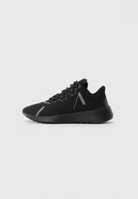 Zapatilla deportiva negra con suela gruesa, parte delantera con cordones y detalle de franja reflectante en ángulo en el costado y la zona de los dedos.