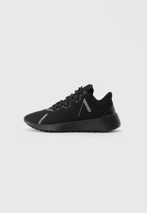 Zwarte sportieve sneaker met dikke zool, vetersluiting aan de voorkant en reflecterende schuin gestreepte details aan de zijkant en de teen.
