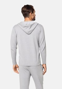 Felpa grigia con zip frontale e cappuccio regolabile, realizzata in tessuto morbido, con polsini e orlo a costine. Design semplice e funzionale.