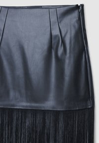 Schwarzer Rock aus Kunstleder mit plissiertem Design oben und einem Fransenabschluss unten, mit glatter Textur und metallischem Reißverschluss an der Seite.