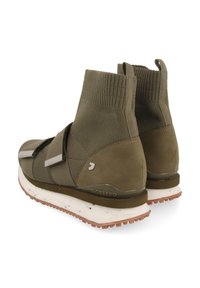 Zapatillas altas de color verde oliva con tejido de punto, correas de velcro, tacón de ante, suela moteada blanca y suela texturizada marrón.