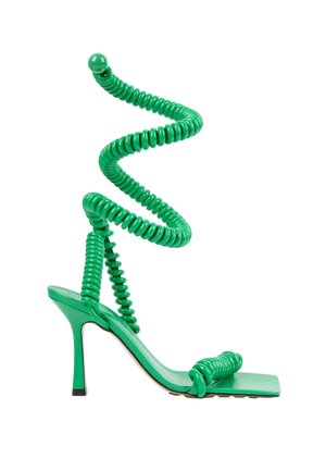 Grøn højthælet sandal med firkantet tå og spiralformede stropper, der vikler sig omkring anklen og foden mod en hvid baggrund.