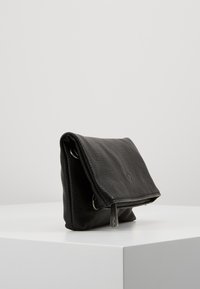 Černá kožená taška s texturovaným povrchem, skládacím designem a stříbrnými kovovými doplňky. Má zipové zapínání a na přední straně je logo.