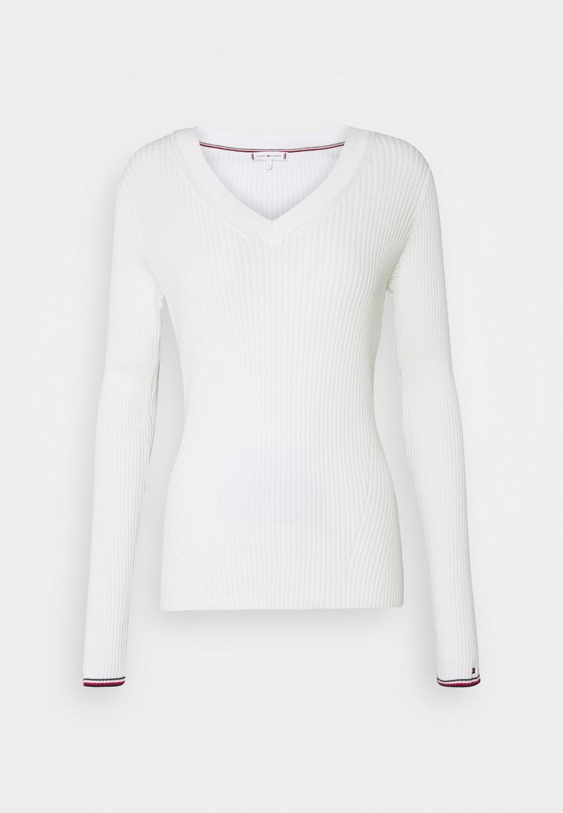 Haut blanc à manches longues côtelé avec un col en V. Présente une coupe ajustée et un détail coloré à l'ourlet des manches. Confectionné dans un matériau extensible.