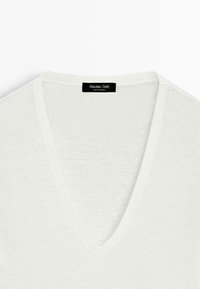 White V-neck casual sweater with lightweight knit fabric and a black label reading "Massimo Dutti" at the neckline.