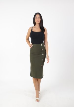 Top in cotone nero fitted con spalline sottili, abbinato a una gonna a matita verde oliva lunga fino al ginocchio, caratterizzata da uno spacco laterale e grandi bottoni argentati.