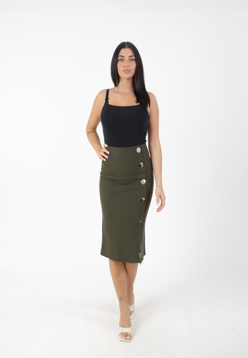Top in cotone nero fitted con spalline sottili, abbinato a una gonna a matita verde oliva lunga fino al ginocchio, caratterizzata da uno spacco laterale e grandi bottoni argentati.