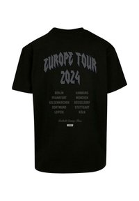 Juodas medvilnės marškinėlis su užrašu "EUROPOS TURAS 2024" ryškiu šriftu, su išvardytomis miestų pavadinimais pilkos spalvos. Klasikinis apvalus kaklas, trumpomis rankovėmis, laisvas kirpimas.