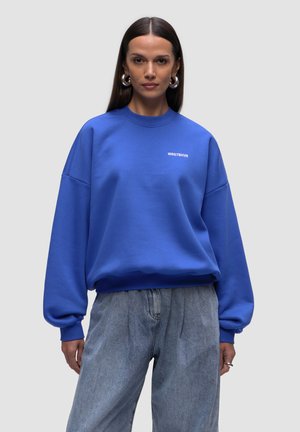 Übergroßer blauer Sweatshirt aus einem Baumwoll-Mischgewebe, mit rundem Ausschnitt und gerippten Bündchen. Weiße Logodetails auf der Vorderseite.