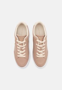 Paire de baskets en cuir beige avec lacets et semelles blanches, vue de dessus, montrant des colliers rembourrés et des semelles intérieures de marque.