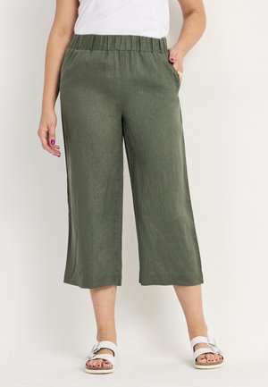 Grønne linned cropped bukser med elastisk talje, sidelommer og en afslappet pasform. Bæret med hvide sandaler.