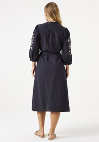 Marineblaue Midi-Kleid aus leichtem Stoff mit Puffärmeln, bestickten Blumenmotiven auf den Schultern und einer taillierten Taille.