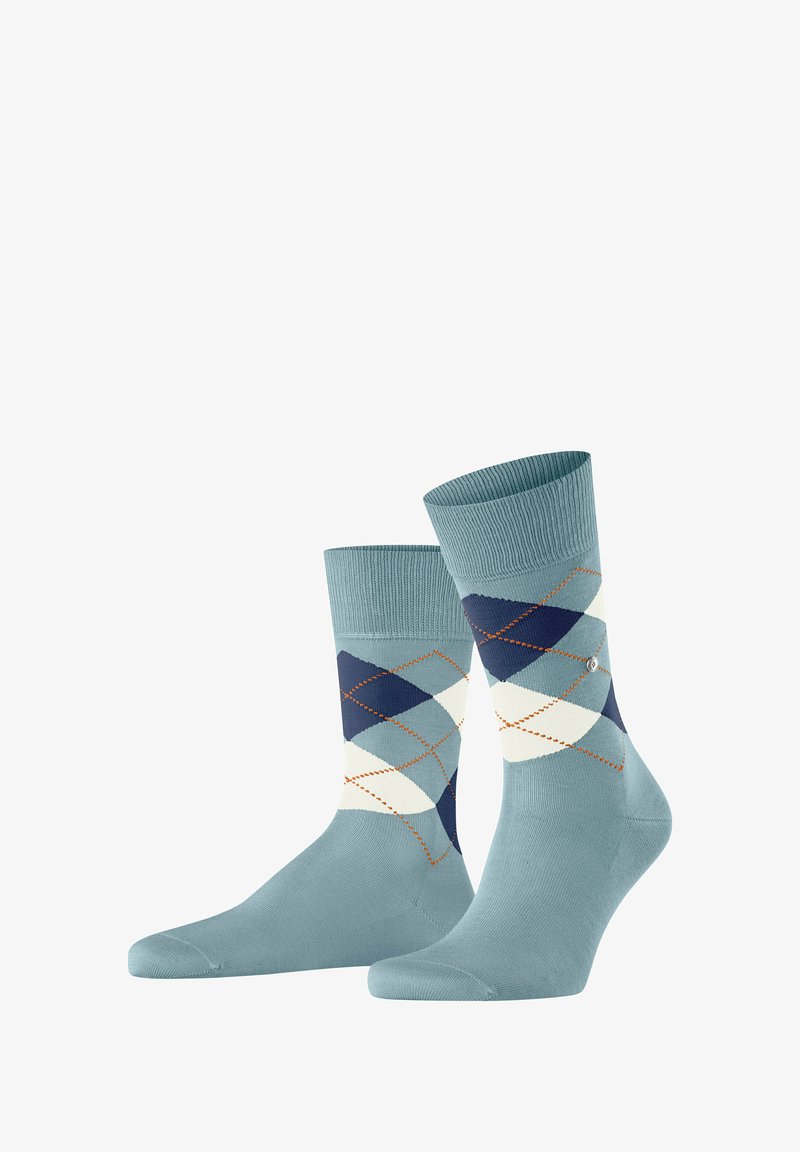 Chaussettes bleu clair avec un motif argyle en marine, crème et teal, avec un contour en losange orange. Poignet côtelé et texture lisse.