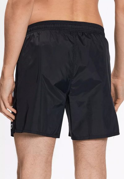 Pantaloni da nuoto neri realizzati in un tessuto leggero e resistente all'acqua. Presentano una vita elastica e tasche con cuciture laterali con un branding minimo.